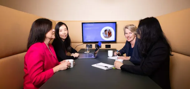 A group of female co-workers working collaboratively together at a desk.
