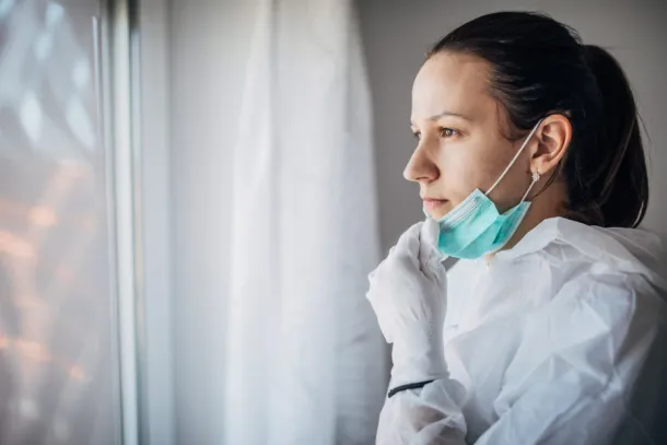 Worried doctor in protective suit, looking through the hospital window.