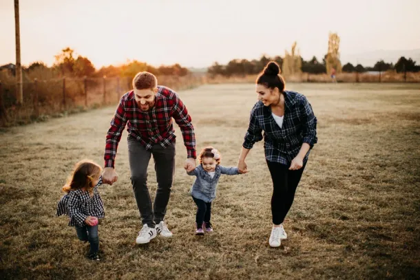 Parents carrying kids, playing on meadow