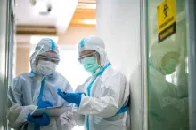 Asian doctor holding checking coronavirus or covid-19 infected patient name list sheet in quarantine area in hospital