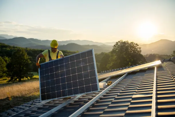 Technician fitting solar panels to a house roof.