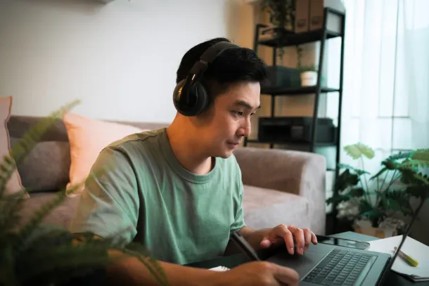 Adult Student man wearing headphone while e-learning on laptop