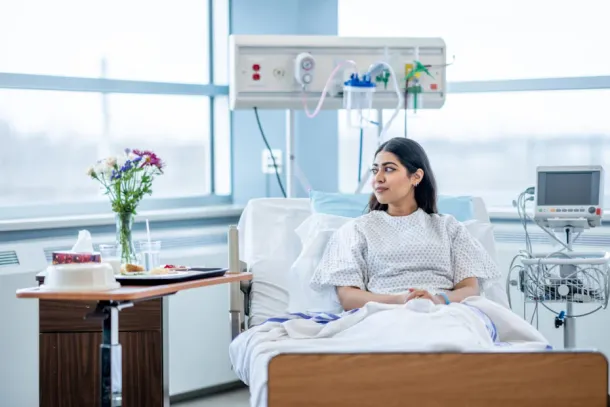 A young person sits up in her hospital bed after surgery