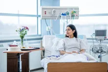 A young person sits up in her hospital bed after surgery