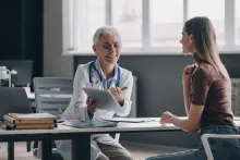 Confident female doctor pointing digital tablet while consulting patient in the medical office.