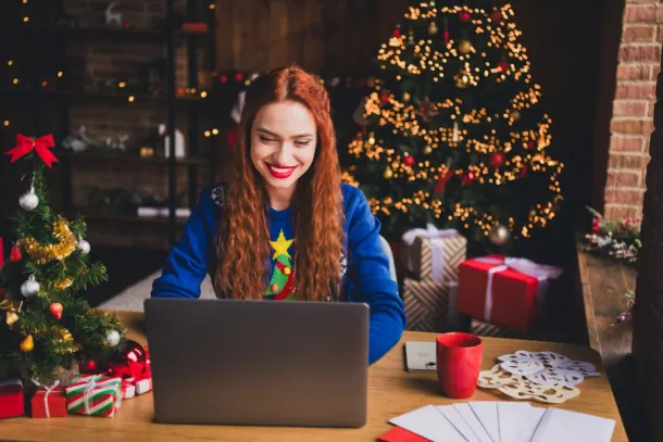 Photo of a girl working on her laptop enjoying a cozy christmas setting