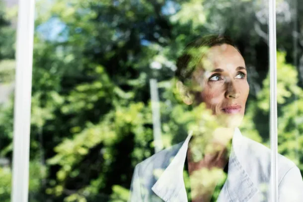 Thoughtful businesswoman standing by glass window in office