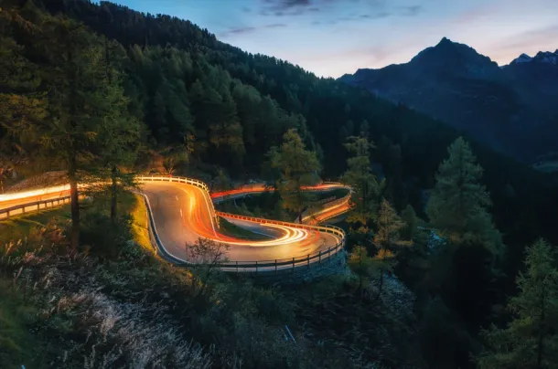 The winding mountain road with light tracks from cars at the evening, Maloja Pass, Switzerland