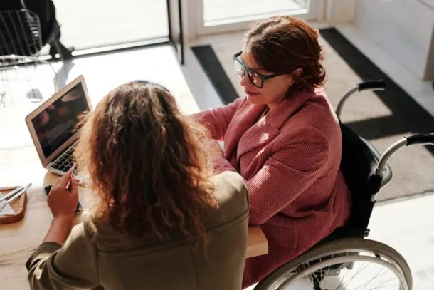 A women in a wheel chair talking to a friend at a cafe.